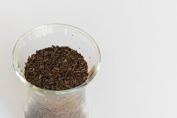Ceylon black tea. Scattered black tea on a white background. Black tea in a glass. Isolated. Dried herbs.