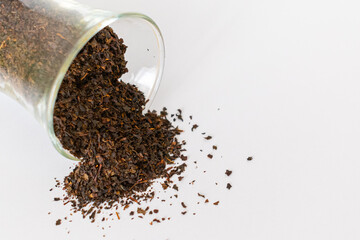Ceylon black tea. Scattered black tea on a white background. Black tea in a glass. Isolated. Dried herbs.