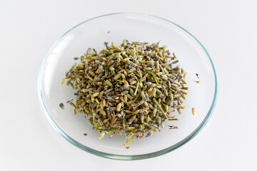 Lavender tea, dried lavender, herbal tea, green tea. Dried herbs in a glass bowl. Glass plate. Dried lavender. On a white background. Isolated. Close up. Top view.