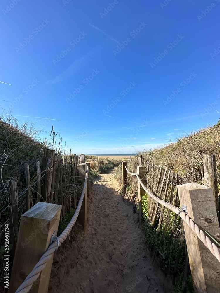 Sticker Pathway between the sand dunes leading onto the beach with a blue sky background. Taken in Lytham Lancashire England. 