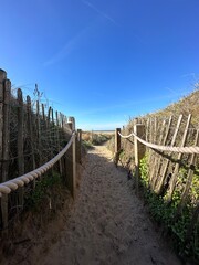 Pathway between the sand dunes leading onto the beach with a blue sky background. Taken in Lytham Lancashire England. 