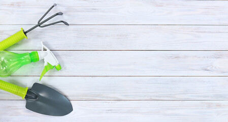 Shovel, rake and spray gun for gardening on a wooden background. Gardening tools on light wooden...