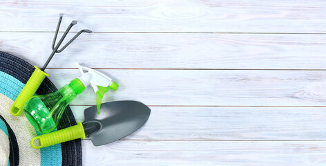 Shovel, rake and spray gun for gardening on a wooden background. Gardening tools and a hat on a...