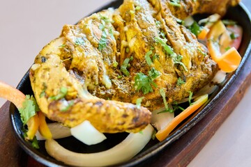 Closeup of grilled eggplants with vegetables in a black plate on the table