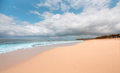 Empty tropical sandy beach and clear sea background with traditional balinese boats at amazing sunset - Bali, Indonesia