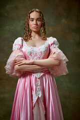 Shot of beautiful woman wearing vintage pink dress and standing with folded hands over vintage texture background. Medieval evil queen © Lustre Art Group 