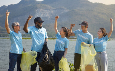 volunteers holding,doing hands up together for powerful volunteering charity,a diverse group of volunteers join together to cleanup the sand beach,collect garbage,separate waste.concept for earth day