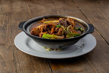 Closeup of beef with a sauce and vegetables on a glass plate