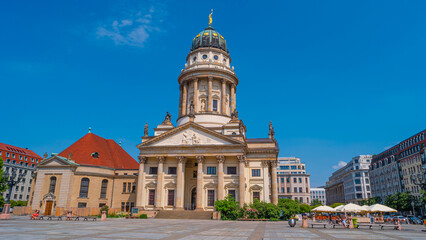 Fototapeta na wymiar View over the Gendarmenmarkt in Berlin with French Cathedral in historical and business downtown at summer sunny day and blue sky.