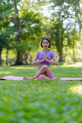 Young Asian woman doing yoga in the garden for exercise and good health. In the park Asian fitness woman doing yoga and relaxing with sportswear in green park in summer