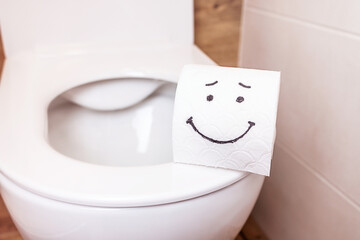 a roll of toilet paper with a happy face hanging on a white wall in the bathroom