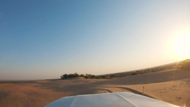 4K POV of a vehicle dune bashing on the sand dunes of the Thar desert at Jaisalmer in Rajasthan, India. Car moves on the desert during the day. Extreme adventure in the desert background.	