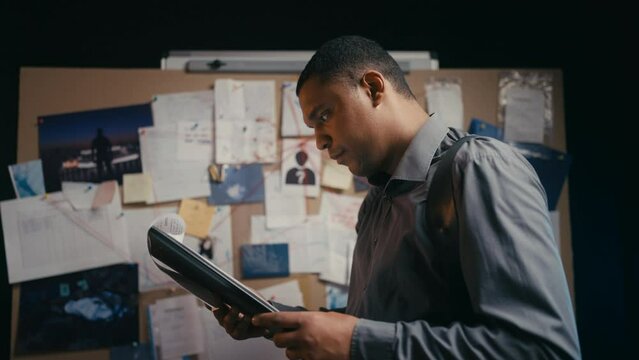 African American detective looking through crime scene logs, evidence list