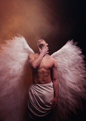 Young strong angel with white wings from heaven. Angel with muscular body. Sensual man