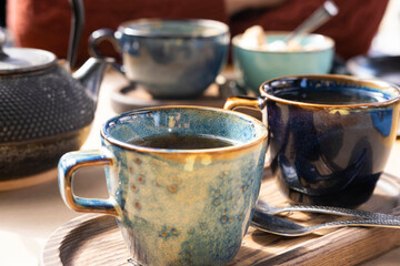 Brewing and Serving Tea. Teapot Poured Green Tea Blue Ceramic Cup on Wooden Cafe Table. Two Pottery Handmade Mugs Early in the Morning. Trendy Authentic Porcelain Set. Breakfast Concept. Tea Time