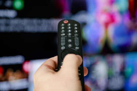 Controle de tv acionando para ligar e assistir series e filmes na televisão smart com fundo borrado.	