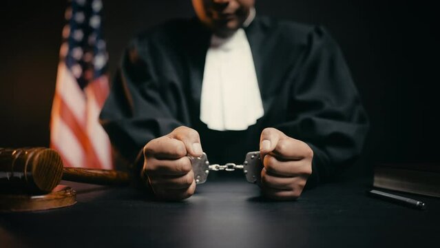 Cuffed judge sitting in courtroom, corruption in court, flawed judicial system