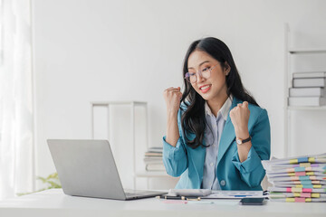 Beautiful Asian girl celebrate with laptop, success happy pose. E-commerce, university education, internet technology, or startup small business concept. Modern office or living room with copy space