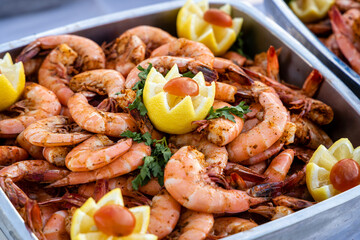 Shrimp with lemon and garnish is served. at an outdoor Buffet.