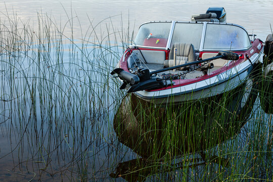A vintage fishing boat with trolling motor tied at dock, with early morning light and dew.