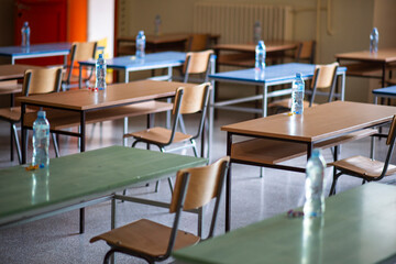 Exam examination room or hall set up ready for students to sit test. multiple desks tables and chairs. Education, school, student life concept.