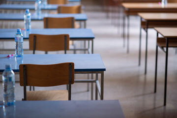 Exam examination room or hall set up ready for students to sit test. multiple desks tables and chairs. Education, school, student life concept.