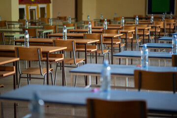 Exam examination room or hall set up ready for students to sit test. multiple desks tables and chairs. Education, school, student life concept.