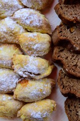 Vertical closeup of brown bread and homemade cookies with icing sugar.