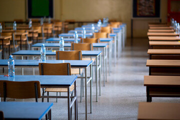 Exam examination room or hall set up ready for students to sit test. multiple desks tables and chairs. Education, school, student life concept.