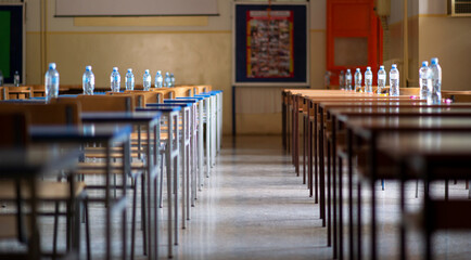 Exam examination room or hall set up ready for students to sit test. multiple desks tables and chairs. Education, school, student life concept.