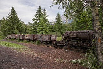 Old rusty train - steam locomotive. An abandoned coal mine overgrown with forest in the mountains....