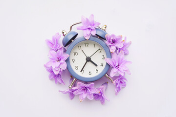 Clock with flowers flat lay. Daylight saving time