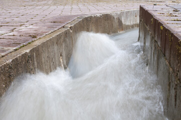 Fototapeta na wymiar Flowing water stream in concrete gutter