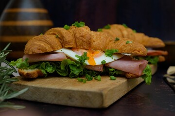 Closeup of a croissant sandwich with bacon and egg on a board