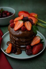 Closeup view of chocolate pancakes with strawberries topping