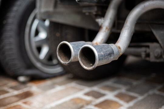 Rusty old chromed car exhaust tips hanging of a dismembered car. Low angle show, selective focus, no people