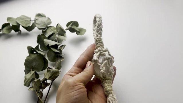 Close up of women's hands holding a macram&eacute; piece. Quartz Macram&eacute; keychain. knots