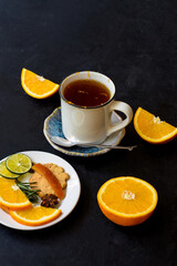 Orange cinnamon tea with crystalized fruits and cookies on black bacground