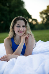 The young  beautiful girl in blue bodysuit, enjoying in the park, looking at camera, with wet hair, posing lying on grass.