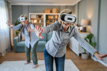 two Women mature senior females at home use virtual reality VR headset