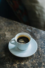 Cup of black coffee on a marble table in a cafe.