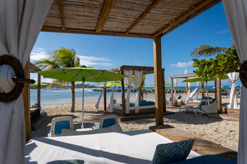 Beach cabanas overlooking the Caribbean Sea. Relax in the shade. Beach, sand, umbrellas, loungers, curtains, palm trees, beach beds. Adrenaline Beach, Labadee, Haiti private resort by Royal Caribbean.