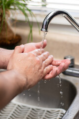 Fototapeta premium Vertical view of close up of person washing their hands in the sink for prevention of virus concept