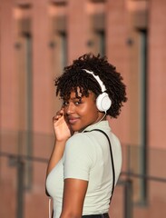 Attractive Latin American teenage girl with curly hair listening to music with white headphones