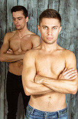Fototapeta na wymiar Two young attractive guys are posing in the studio. Beautiful gay couple in a relationship on holidays with gifts. Love and romance.