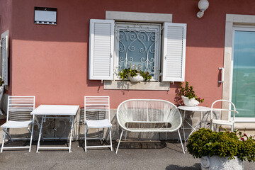 Mediterranean cafe veranda with white outdoor furniture, window with white shutters
