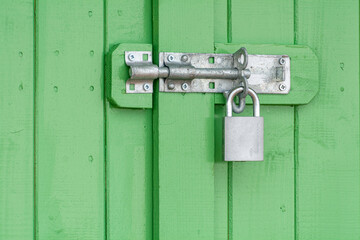 Door Locking Bolt and Padlock on a Green Wooden Door