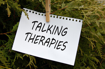 TALKING THERAPIES - words on white paper with clothespin on a green background of branches