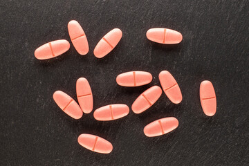 Several medical pills on slate stone, macro, top view.