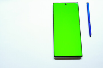 Smartphone mockup with green screen, stylus pen on the side, top view, isolated on white background